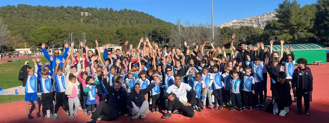 Tout le groupe de l'école d'athlétisme de l'OM Athlétisme, bras levés sur la piste