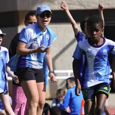 Éducatrice et enfants de l'école d'athlétisme de l'OM, bras levés