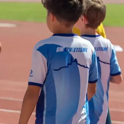 Deux enfants en maillot OM Athlétisme sur la piste, vus de dos