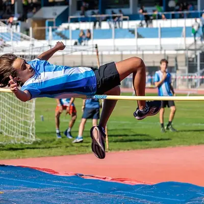Jeune athlète de l'école d'athlétisme franchissant la barre au saut en hauteur